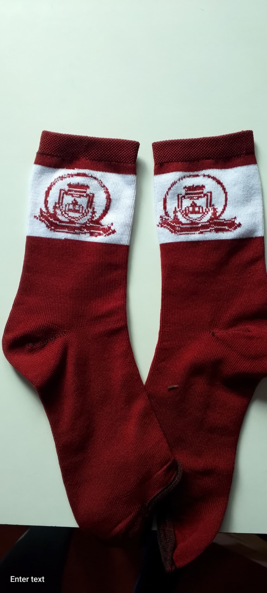 Maroon school socks with a white band carrying a maroon knitted school crest