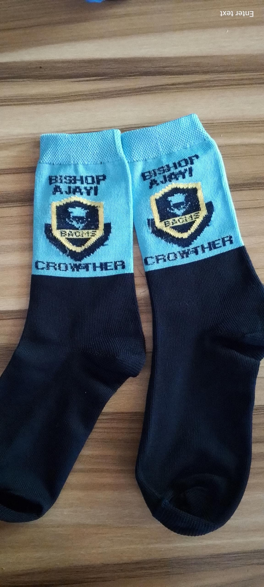 Light blue and black school socks with Bishop Ajayi Crowther name and gold shield crest